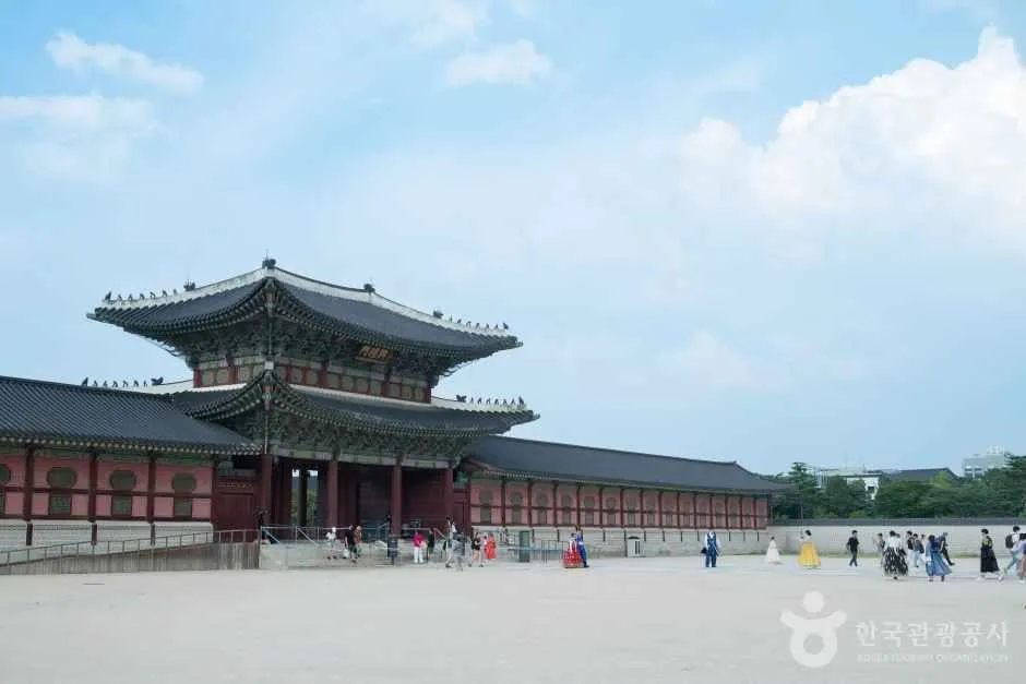 Heungnyemun Gate and the wide forecourt of Gyeongbokgung Palace, with visitors in hanbok walking past