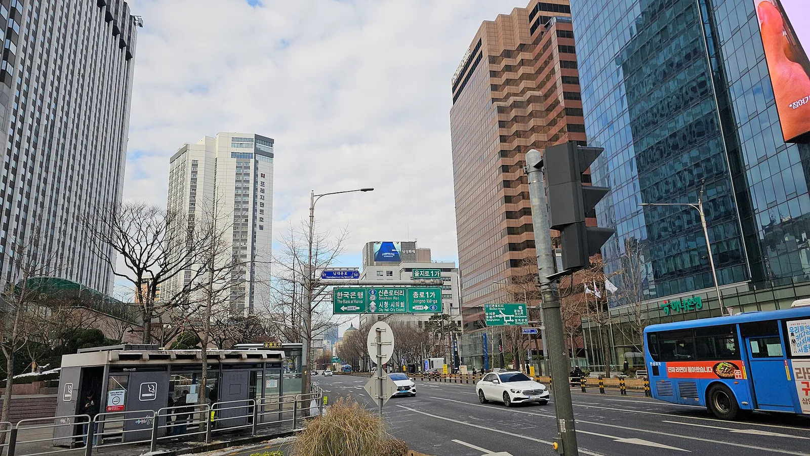 乙支路1街の交差点。高層オフィスビルが並び、道路の上に鍾路1街と市庁の方向を示す標識が掛かっている