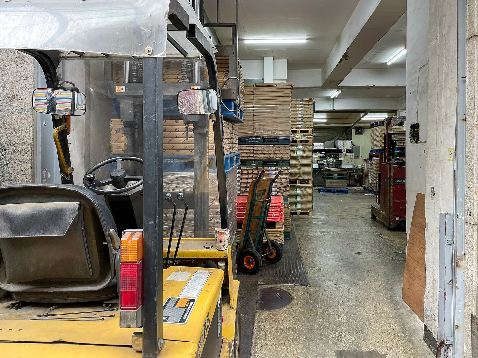 Inside a building in the printing alley, paper stacked to the ceiling behind a forklift