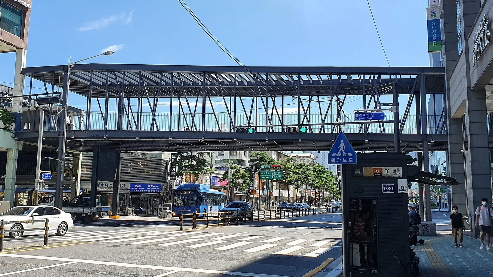 A steel-framed pedestrian bridge crossing above Euljiro, cars and buses passing underneath