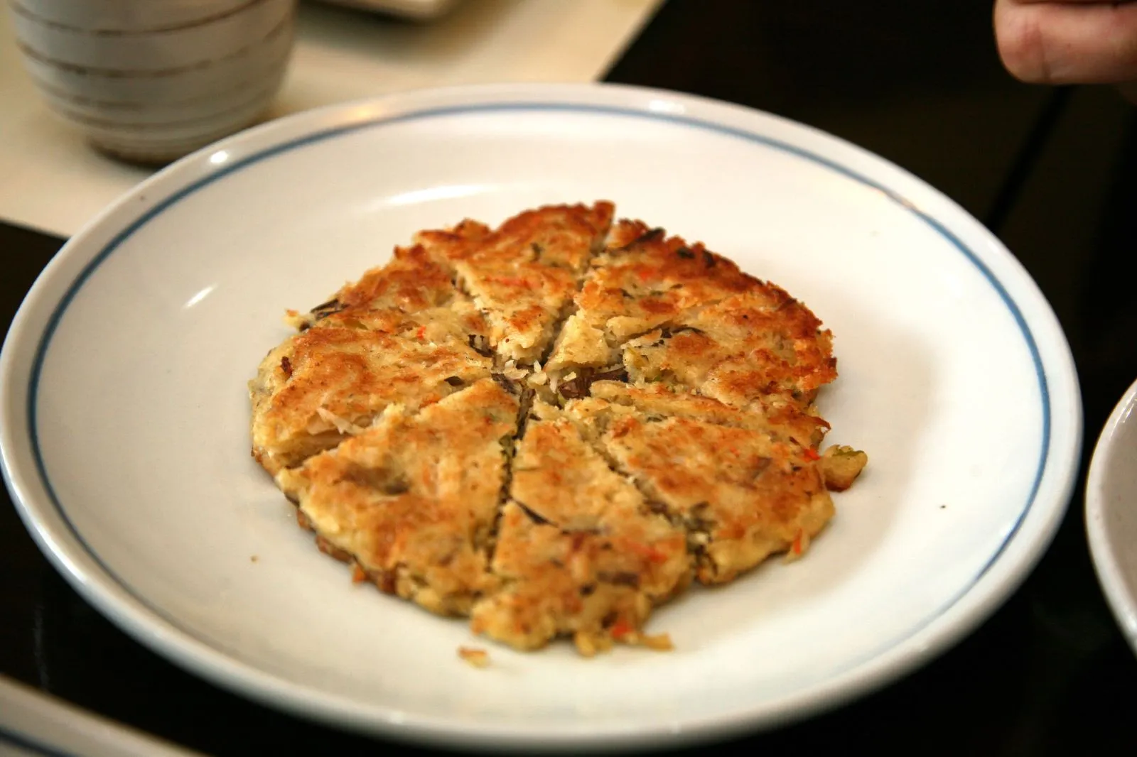 A golden-fried mung bean pancake cut into pieces and served on a plate