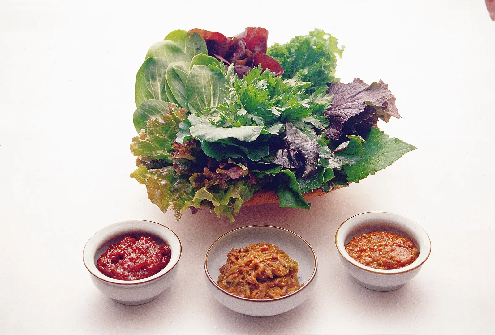 A platter of lettuce and other wrap vegetables served with a bowl of ssamjang paste