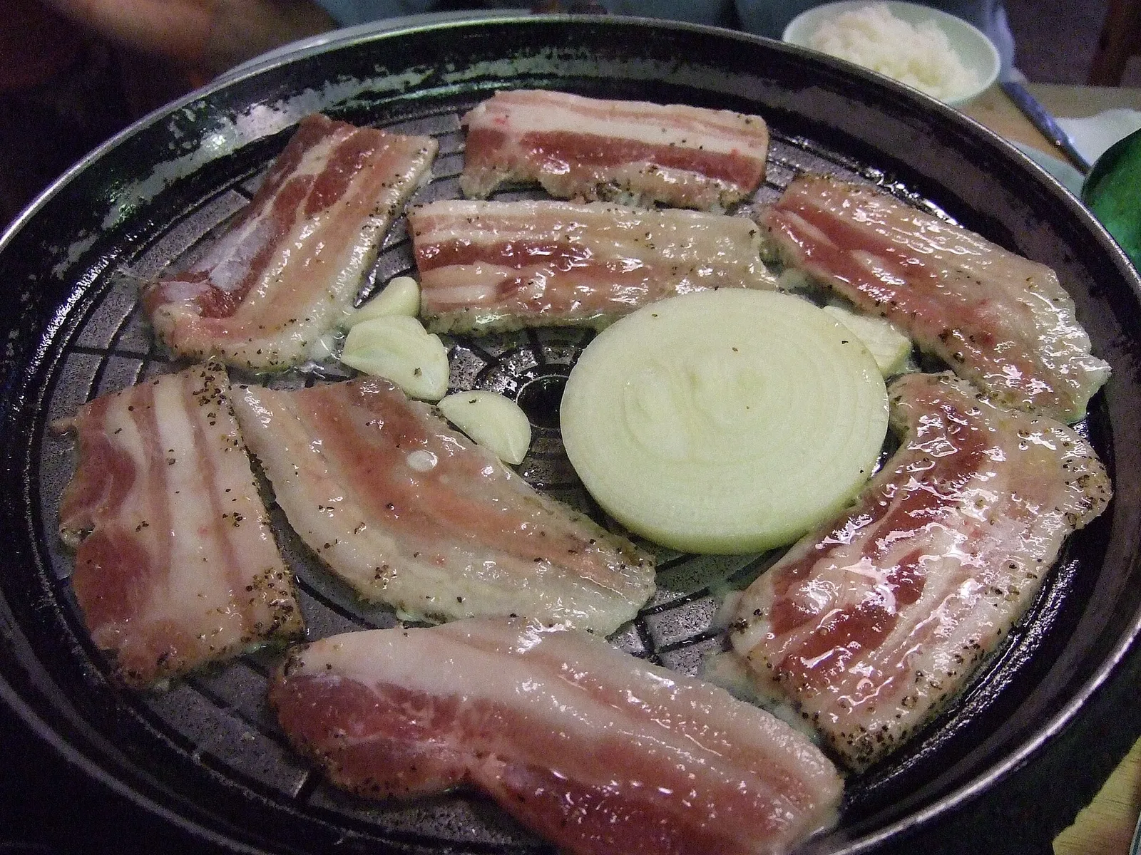 Samgyeopsal, sliced pork belly grilling at the table