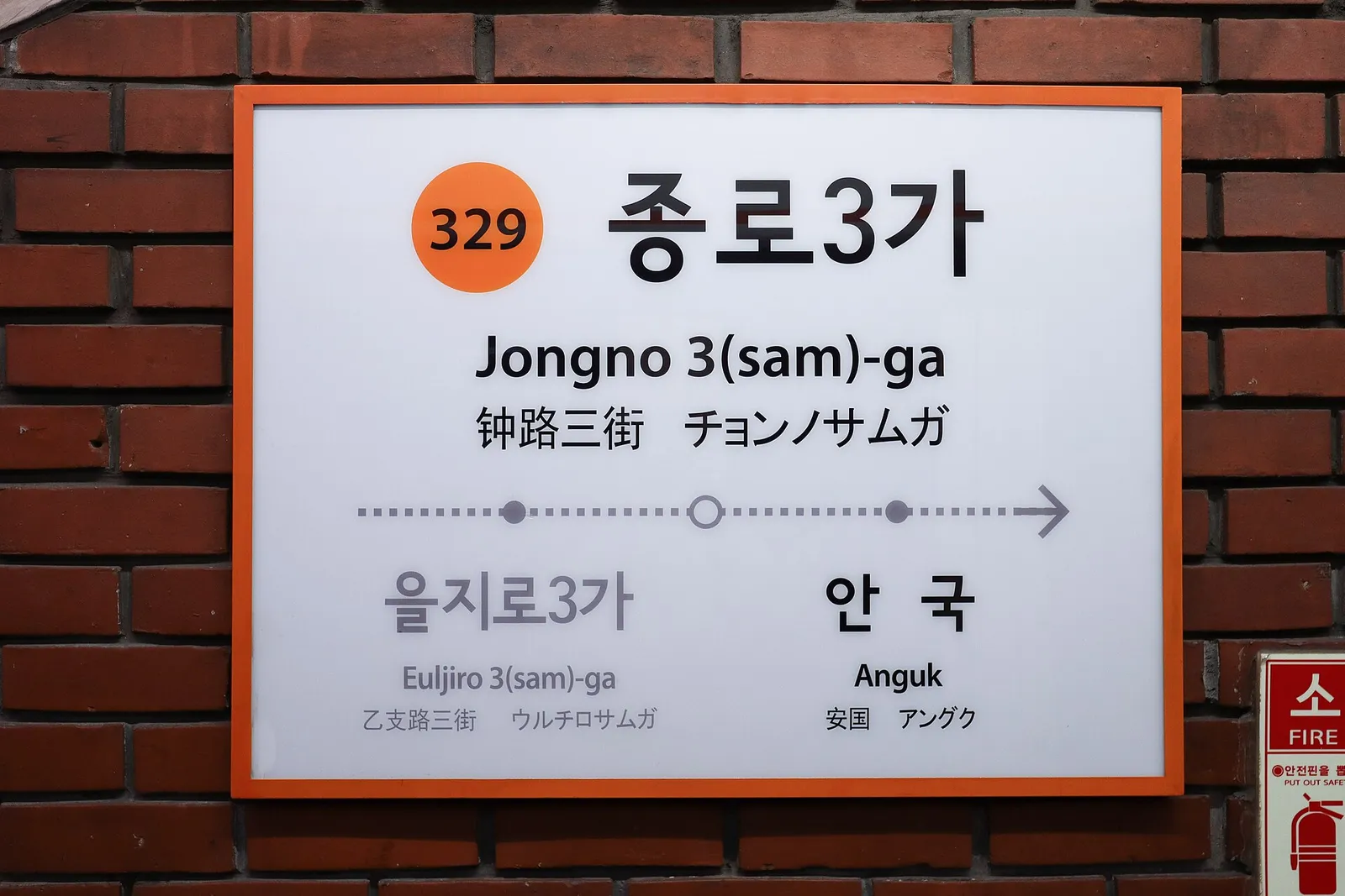 A platform at Jongno 3-ga Station, a train pulling in behind the platform screen doors