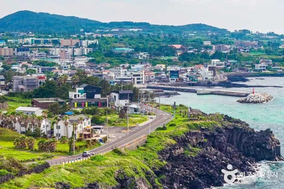 涯月の集落沿いに曲がる海岸道路と、青緑の海、防波堤