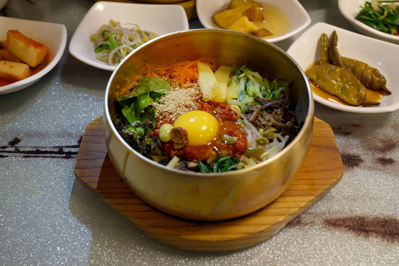 A brass bowl of Jeonju bibimbap with vegetables arranged in colour segments over rice