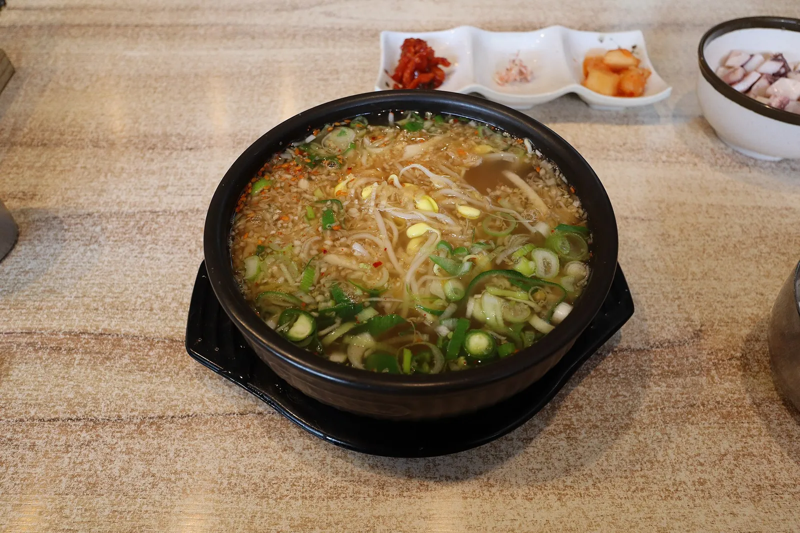 A bowl of kongnamul gukbap, bean sprout soup over rice, with side dishes