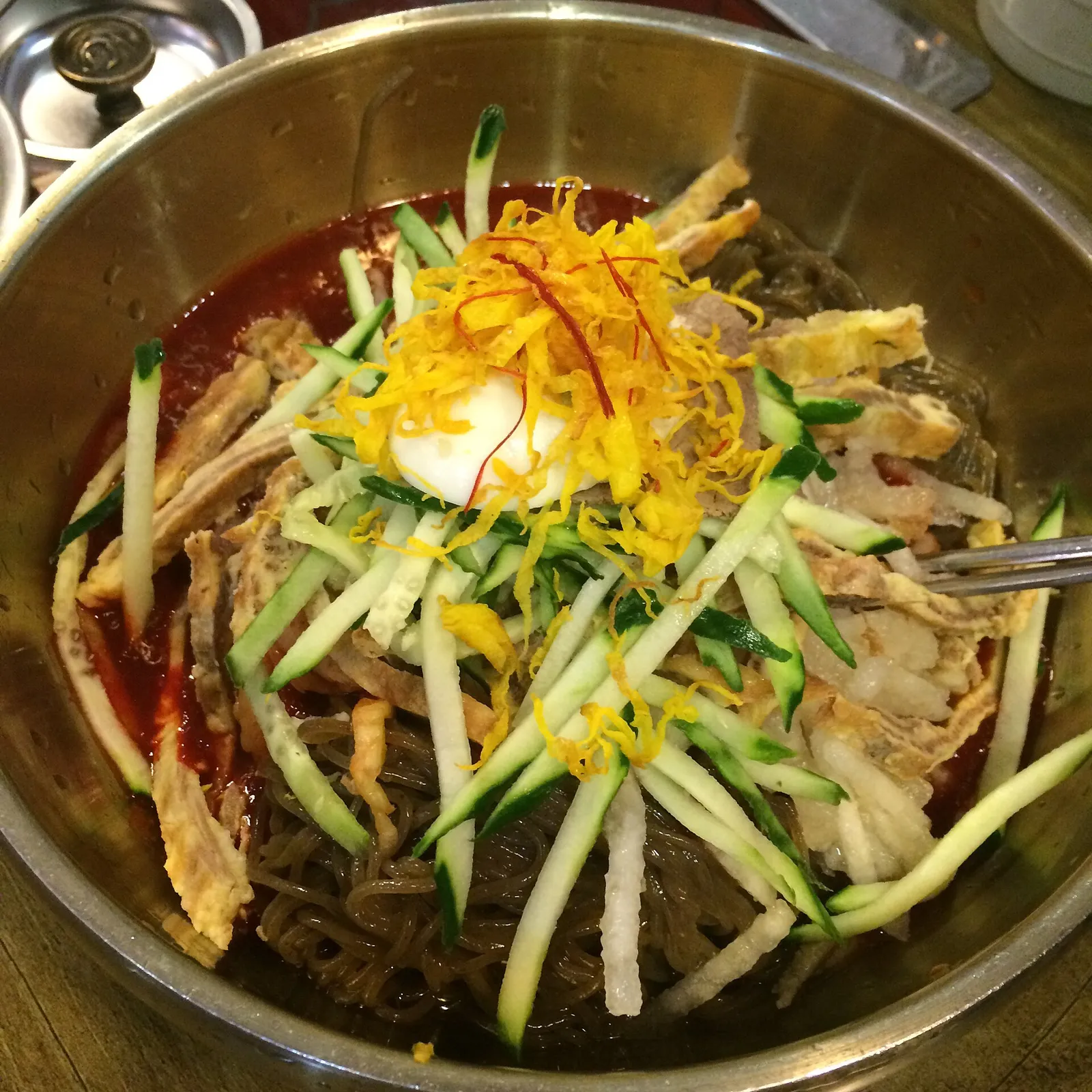 赤いたれで和えて出された晋州のビビン冷麺と、その上にのった具