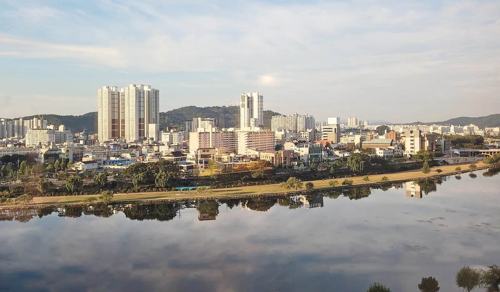 南江の対岸から見た晋州の市街地、水面に映るマンション群と低い市街の建物、奥に連なる山並み