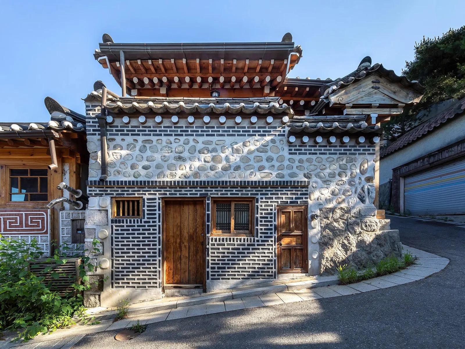 A traditional hanok house with wooden doors on a sloping street in Bukchon