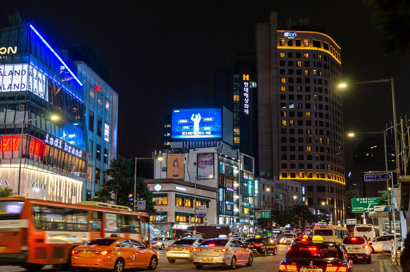 Namdaemun-ro in Myeongdong at night with lit shopfronts and traffic