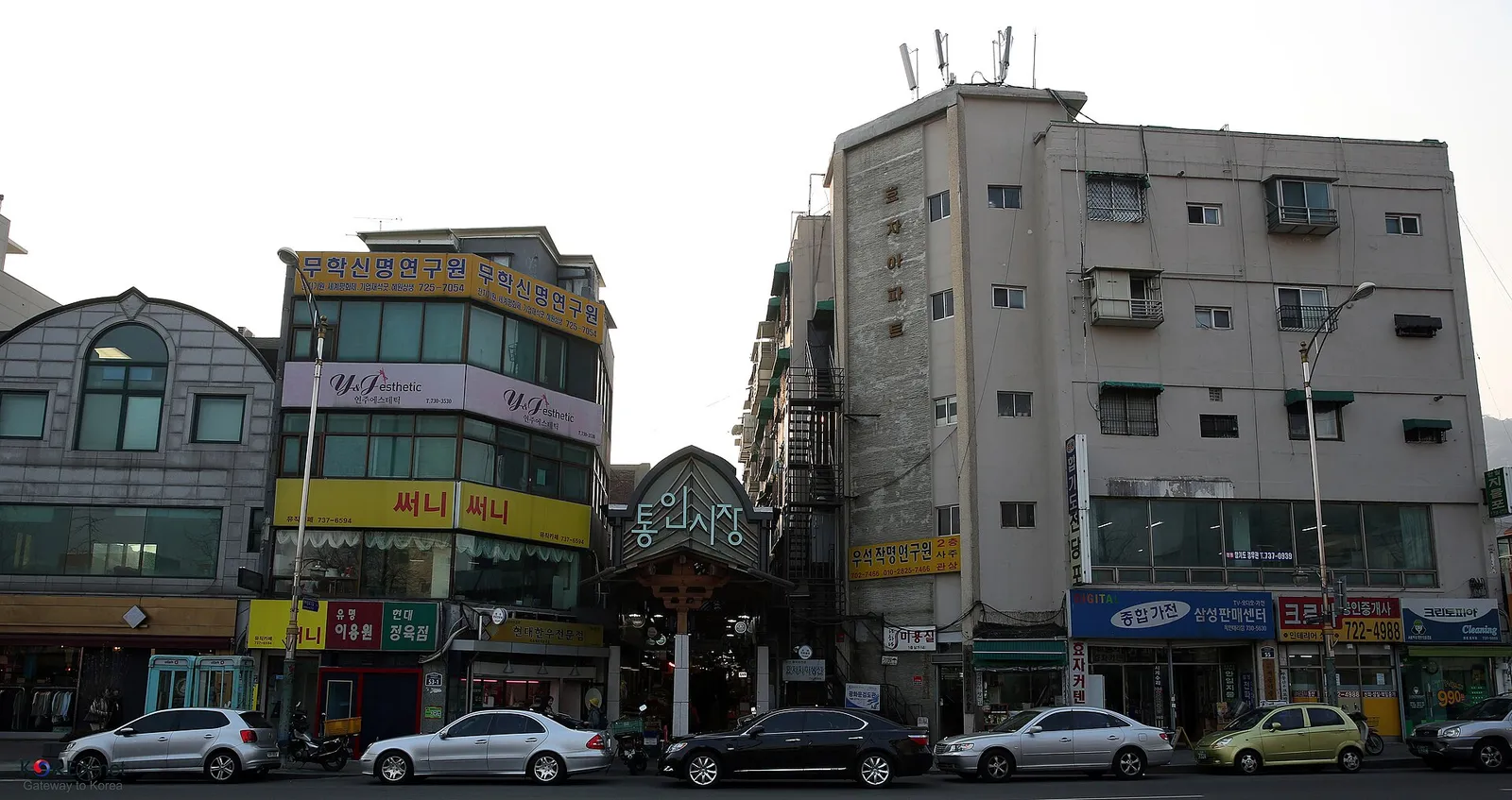 The tiled-roof entrance sign of Tongin Market, with old shop buildings lined up on either side