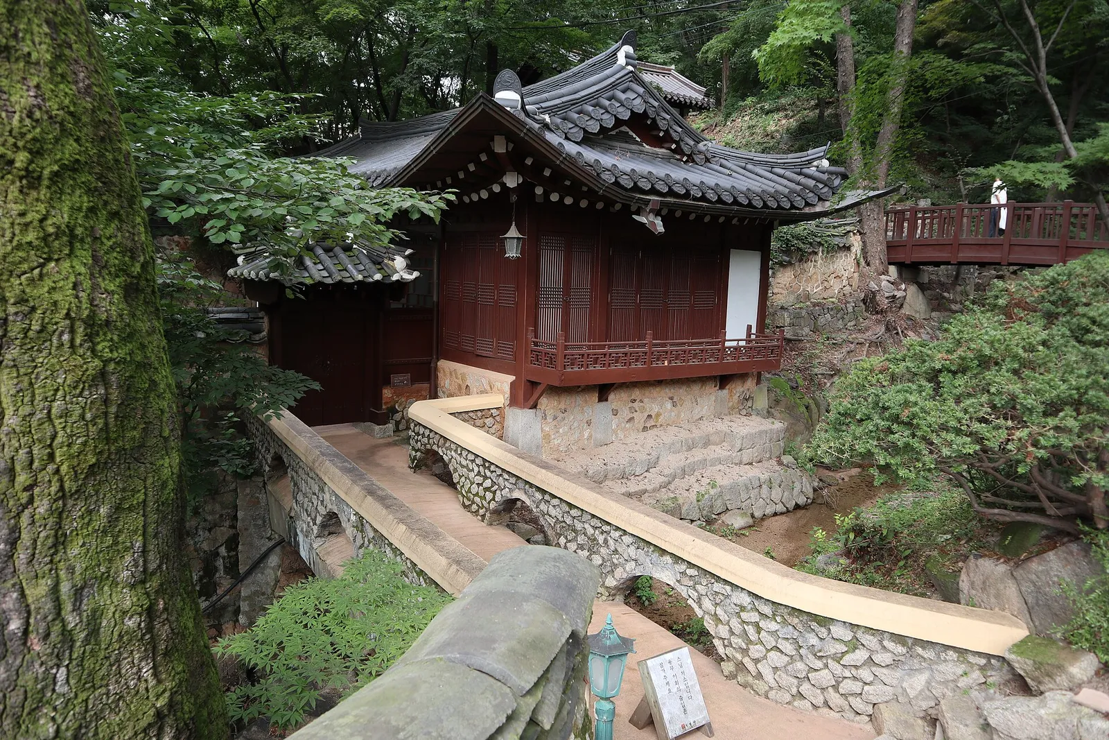 渓谷の上に建つ吉祥寺の木造の堂。石橋と瓦屋根が木々に囲まれている