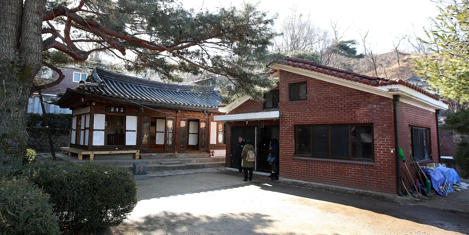 尋牛荘の母屋。瓦屋根の下に扁額が掛かり、隣に赤れんがの管理棟が建っている