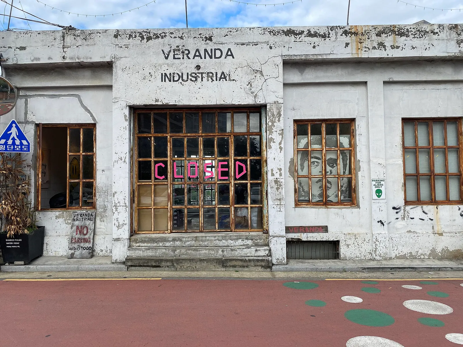 A CLOSED sign in pink letters on the peeling wall of an old building