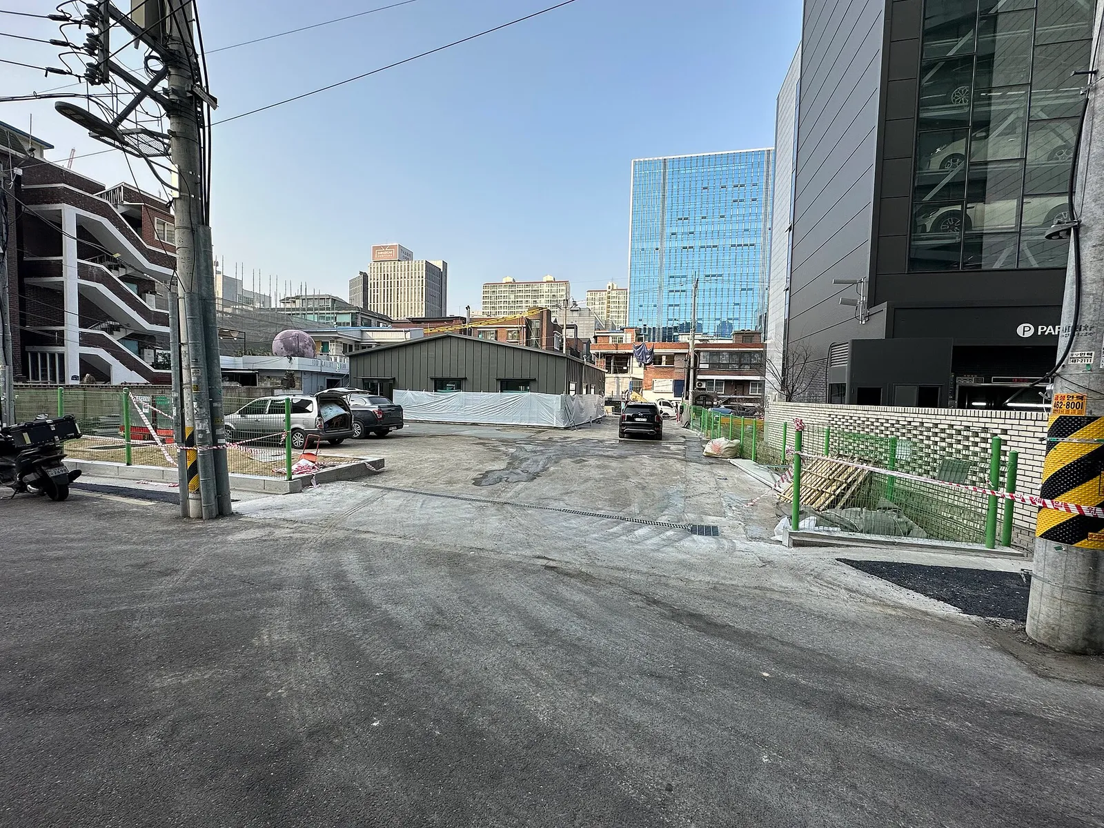 A glass high-rise seen across an empty lot where demolition and construction are under way