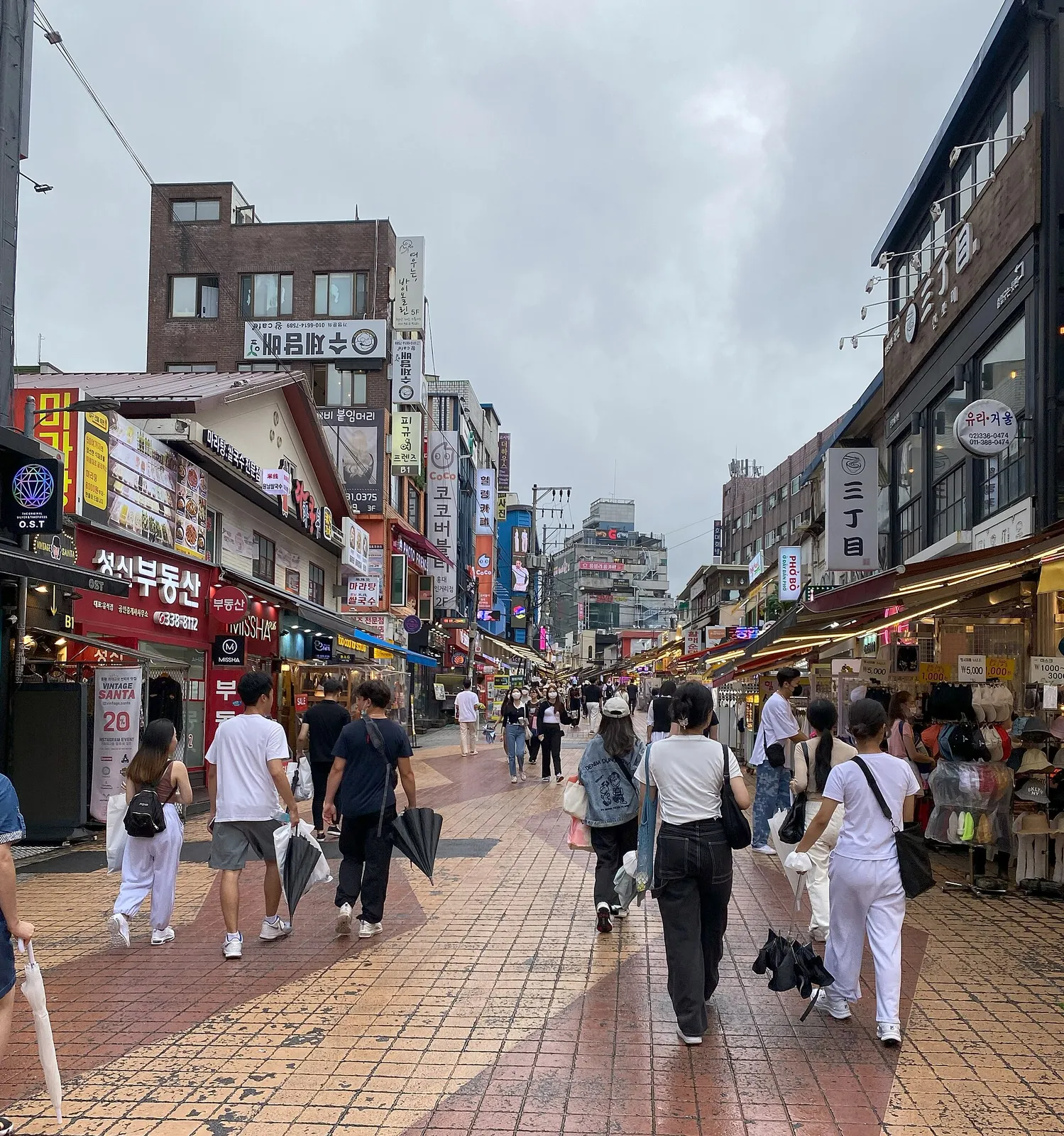 People walking down a busy shopping street in Hongdae