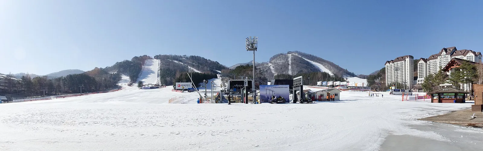 晴れた空の下に広がる龍平リゾートの雪原と、山の斜面に沿って伸びるスロープ、右手にリゾートの建物