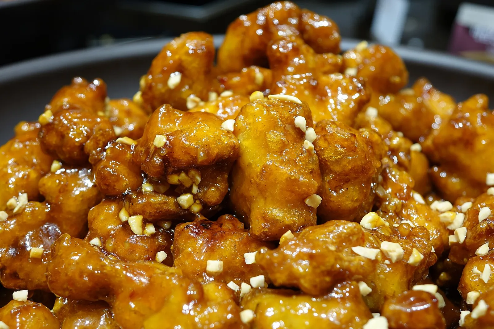甘いタレをまとった鶏の唐揚げに刻んだナッツを散らした一皿